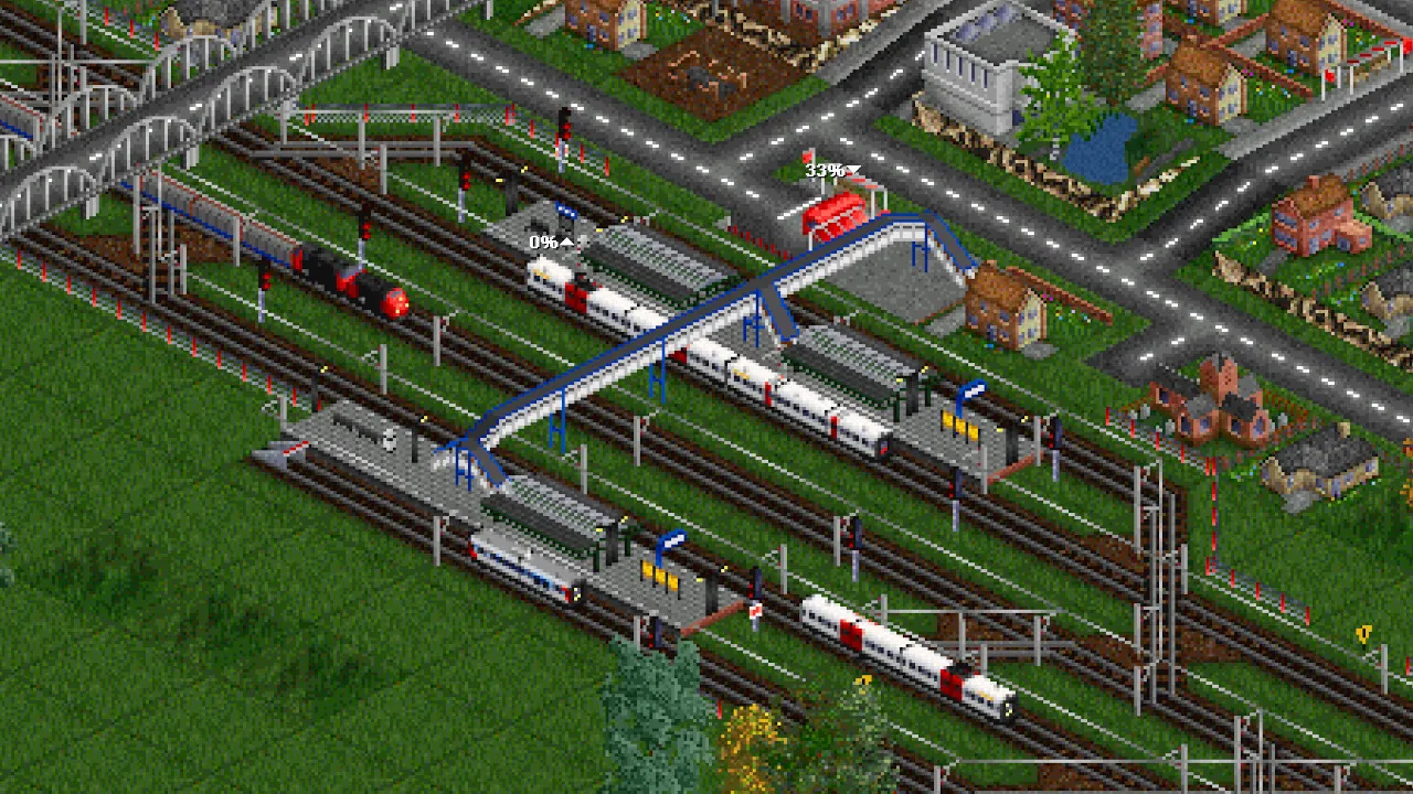 An OpenTTD station with several trains on parallel tile-grid tracks, a road bridge over the lines and a town beside it