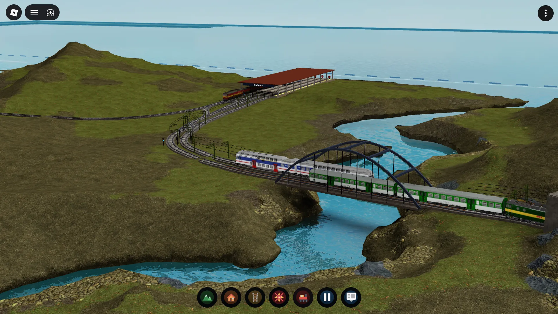 A player-built Rail Island railway with passenger trains crossing an arched bridge over a river