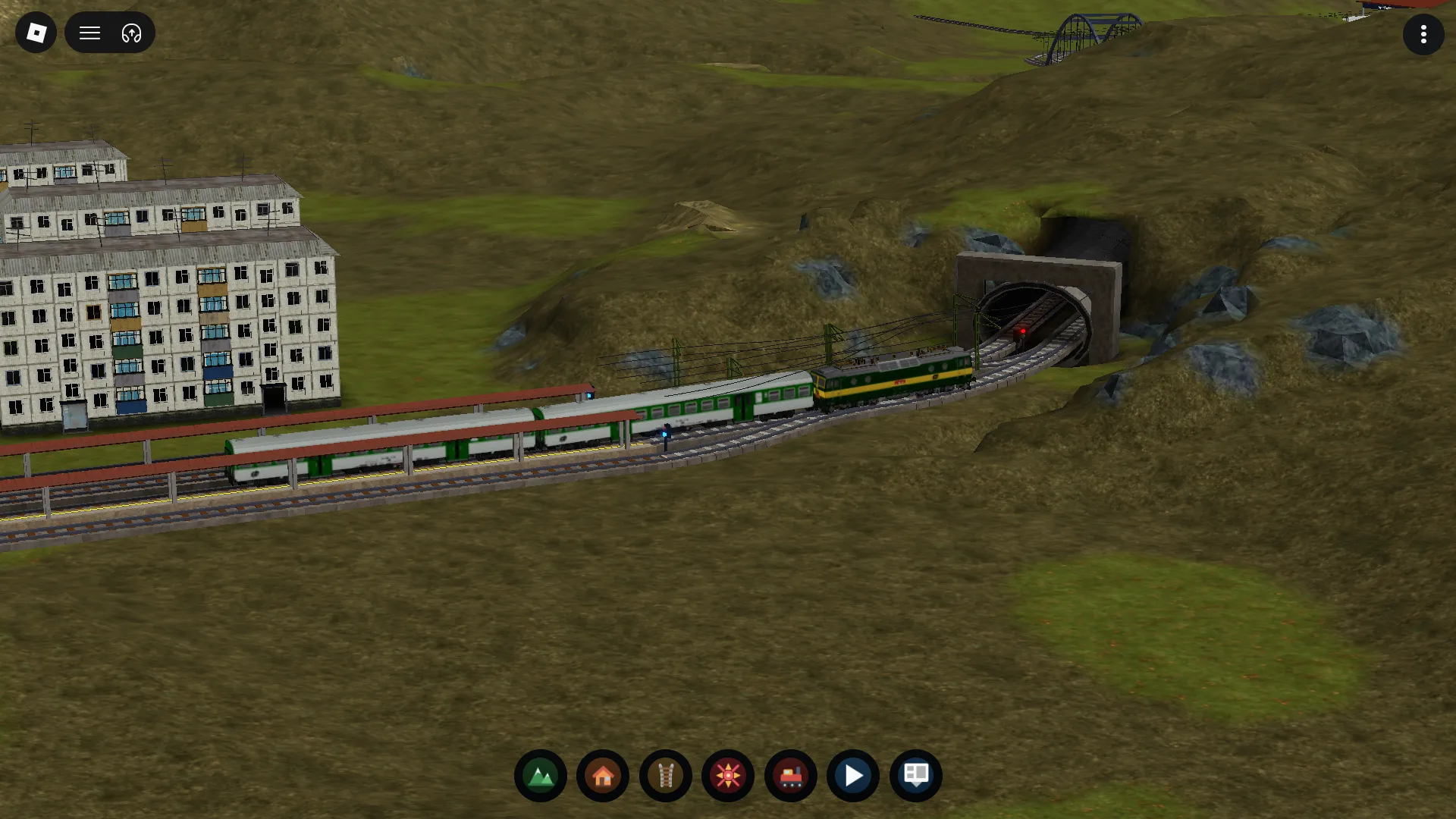 A passenger line runs past apartment blocks toward a tunnel in the slope.