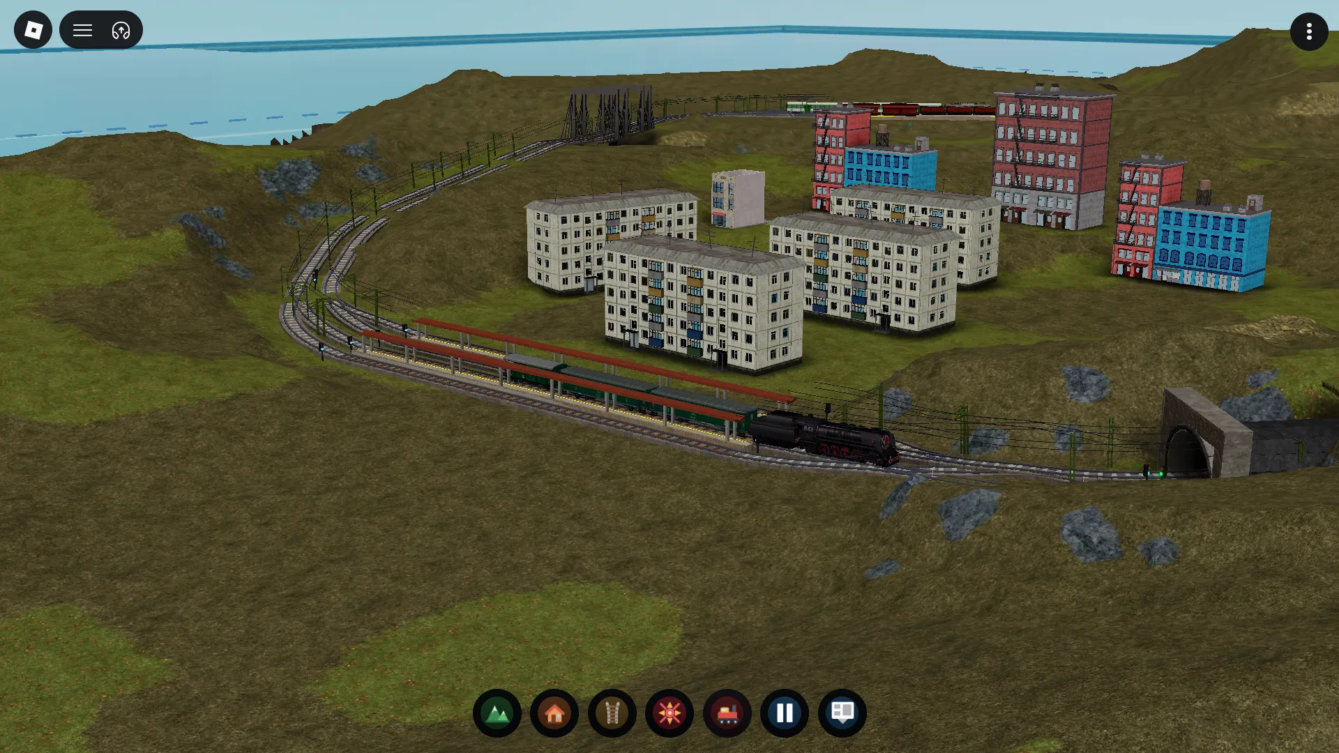 A town loop connects homes, stations and a tunnel mouth on the edge of the hills.